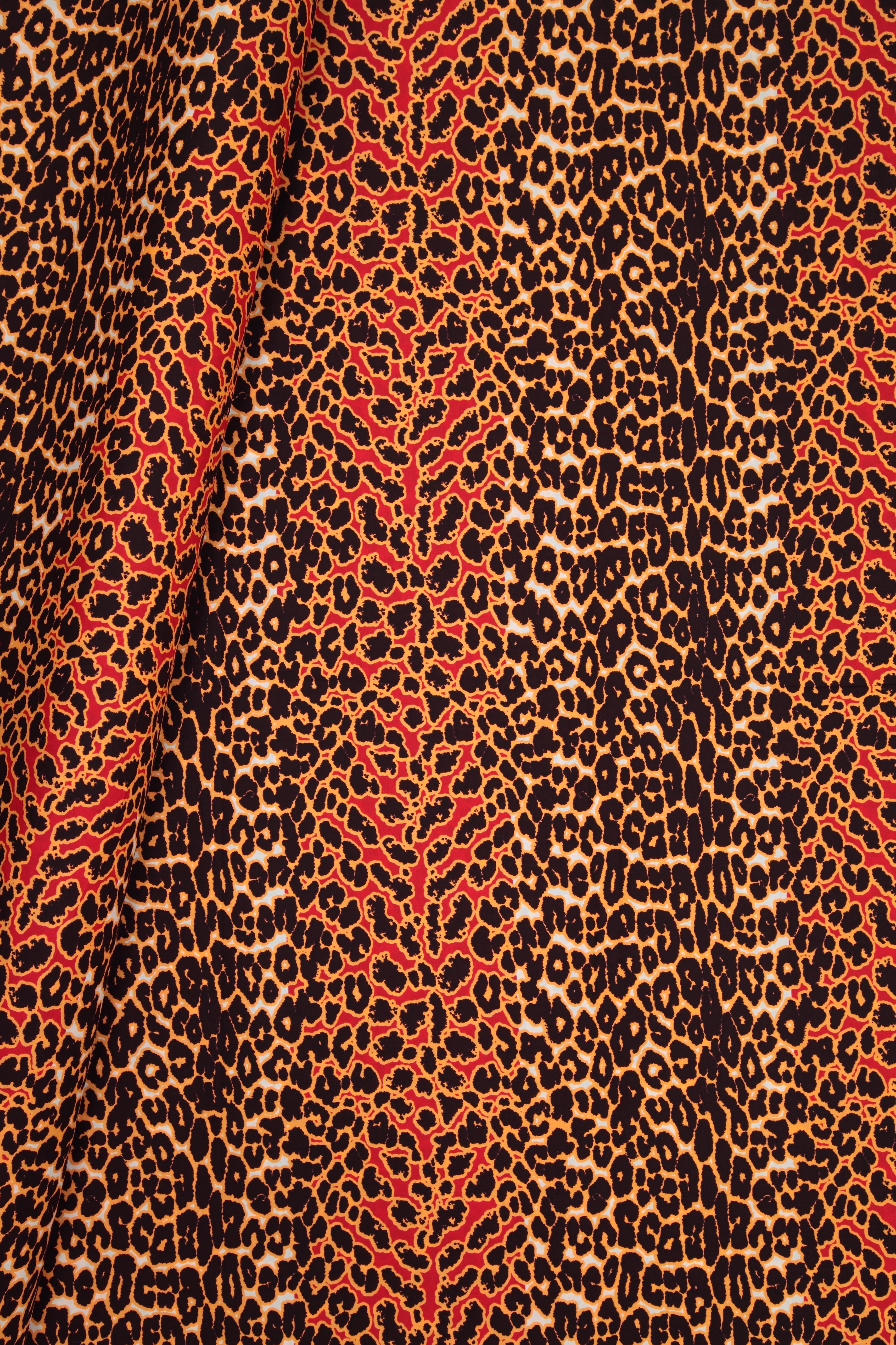 A close-up of a leopard print fabric with a vertical red and orange stripe pattern running through a brown, black, and beige animal print.