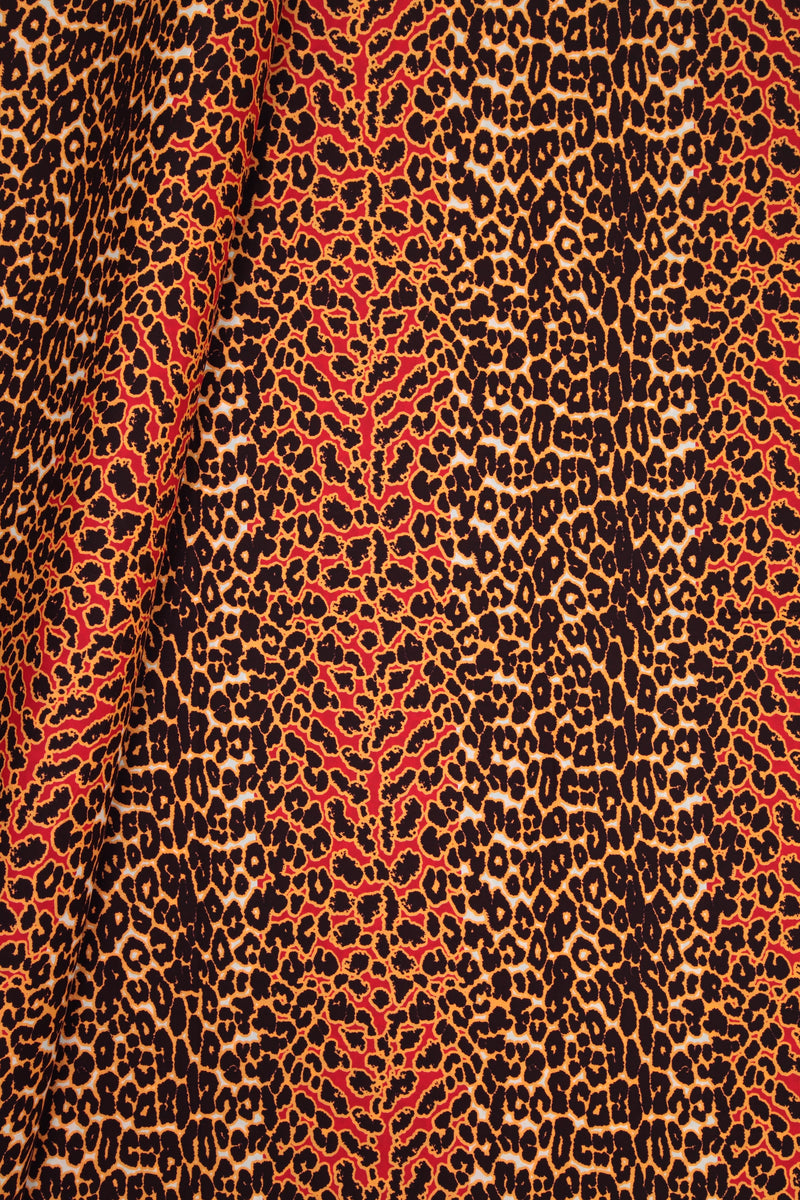 A close-up of a leopard print fabric with a vertical red and orange stripe pattern running through a brown, black, and beige animal print.